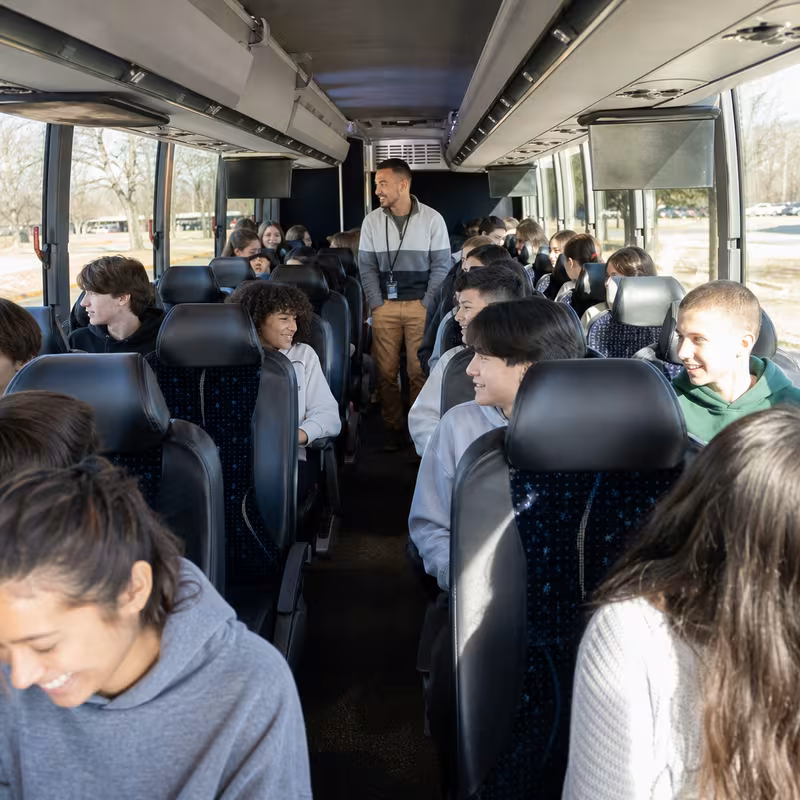 Group boarding a white charter bus for School Transportation transportation in Dallas